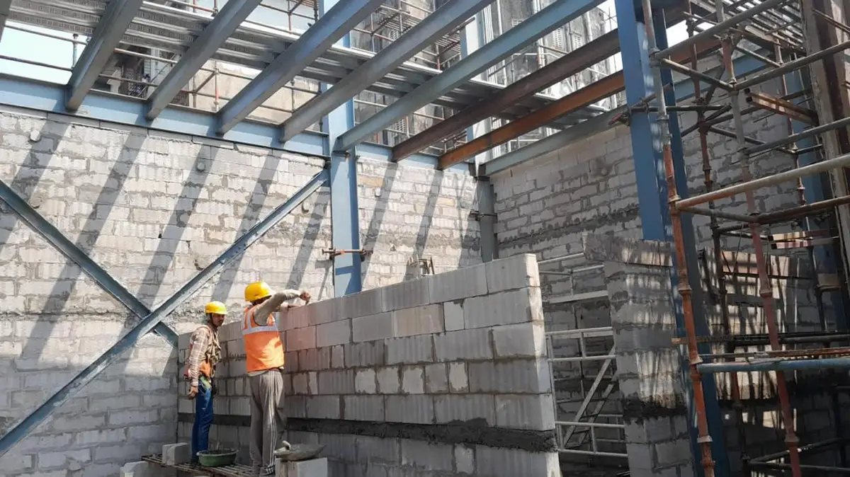 Workers building blockwork walls within a steel structure